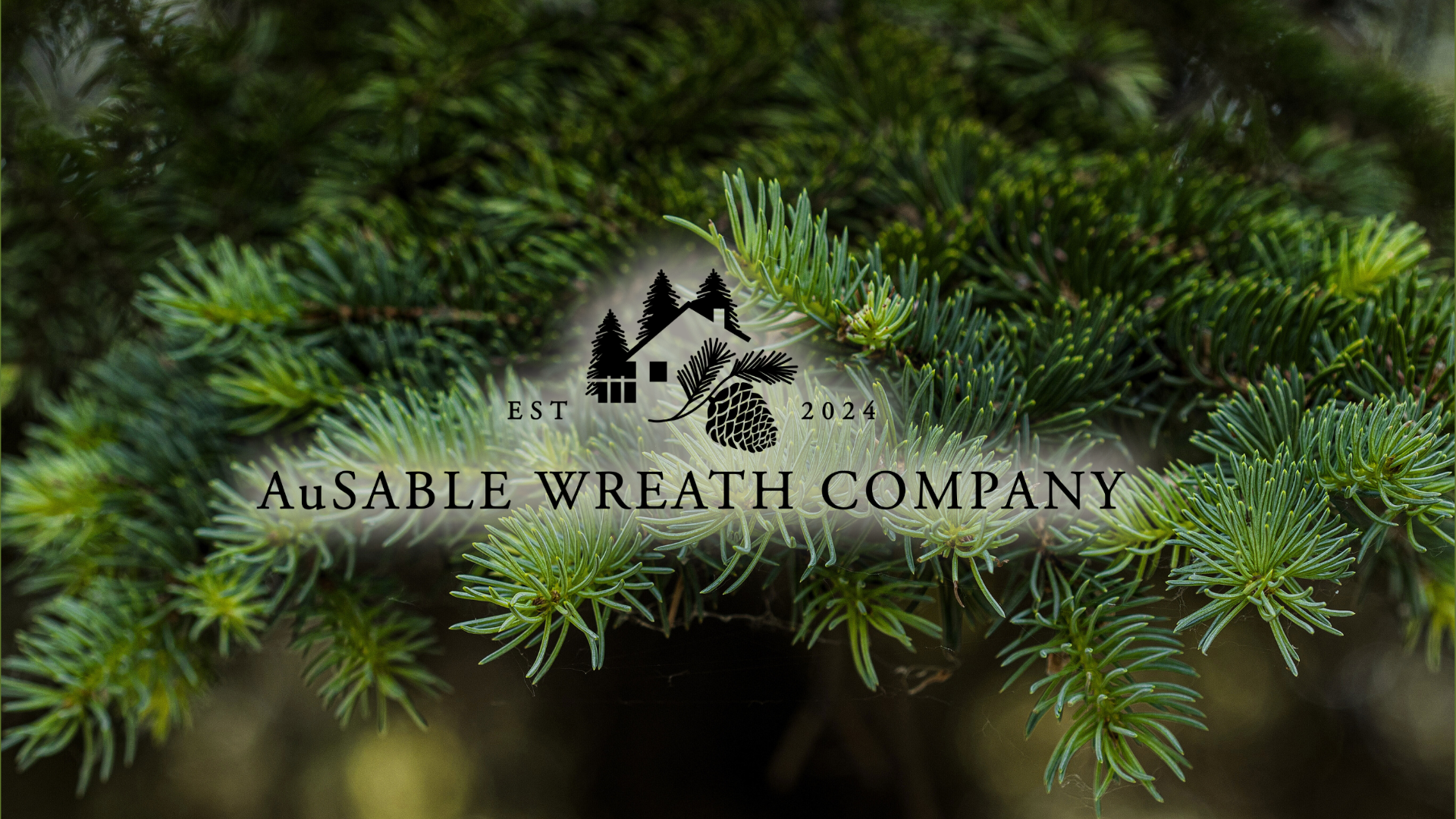 Logo of Ausable Wreath Company on a background of green pine leaves