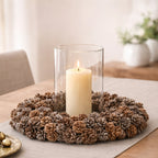 Ausable wreath company hurricane globe on a decorative pinecone wreath with a candle inside on a table
