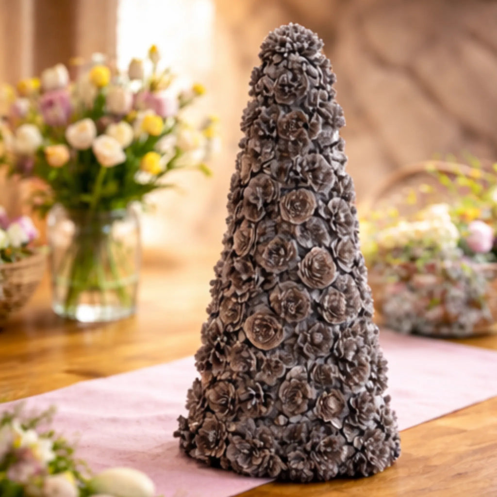 Ausable wreath company Decorative cone made of pinecones on a table with floral arrangements in the background.