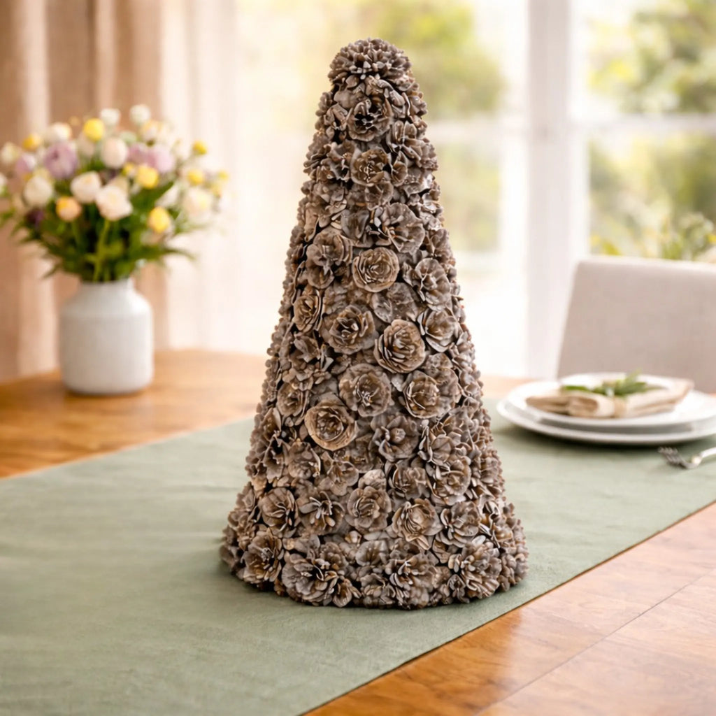 Ausable wreath company Decorative pinecone tree on a table with a vase of flowers in the background